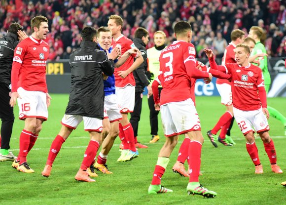 Gaetan Bussmann (blaue Jacke) muss sich nach dem Schlusspfiff der Glückwünsche von Stefen Bell und Yunus Malli (v.l.) erwehren.