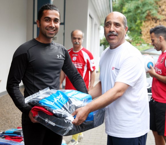 17 Flüchtlinge nehmen derzeit regelmäßig am Trainingsbetrieb bei C-Ligist Vorwärts Orient teil. Malteser Behrouz Asadi (r.) übergibt einem von ihnen, Torwart Peyman Azizirad, sein Austattungspaket.