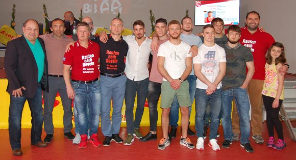 Gruppenbild mit Sportlern und Verantwortlichen des ASV Mainz 88 (v.l.): Zweiter Vorsitzender Stefan Löhner, Cheftrainer Davyd Bichinashvili, Vorstandsmitglied Karani Kutlu (im Hintergrund), Schriftführer und Sportlicher Leiter Marcus Weber, (leicht verdeckt) Beisitzer Dennis Nickolay, Zweiter Vorsitzender Baris Baglan, Tim Müller, Ercihan Albayrak, Ilir Sefaj, Wladimir Remel, Niklas Dorn, Mannschaftskapitän Konstantin Völk, Ruslan Kudrynets und Vorsitzender Tolga Sancakaroglu mit Tochter Ada.