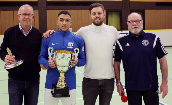 Ihrem Ex-Spieler Dennis de Sousa Oelsner (2.v.l.), der das Team des TSV Schott durch das Turnier führte, durfte die Gonsenheimer Vereinsverantwortlichen (v.l.,) Jochen Mayer, Marvin Bylsma und Hans-Walter Sans den Pokal überreichen.