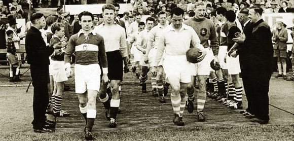 Kapitän Karl-Heinz Wettig (vorne links) führt die 05er zum Jubiläumsspiel im Jahr 1955 gegen Manchester City auf den Bruchwegrasen. Der Torjäger würde am Freitag 93 Jahre alt werden. Torhüter der Engländer ist übrigens der legendäre Bert Trautmann.