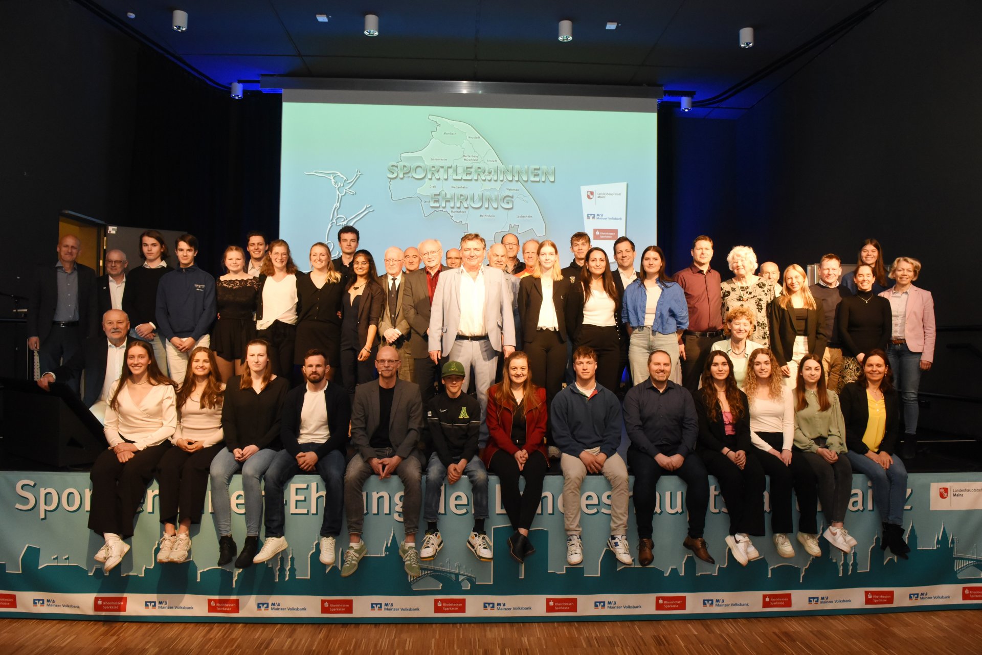 So seh’n Sieger aus: Zum traditionellen Gruppenbild versammelten sich am Ende der Sportlerinnen- und Sportlerehrung der Stadt Mainz alle Athletinnen und Athleten, die im vorigen Jahr entweder  einen DM-Titel gewonnen hatten oder bei internationalen Meisterschaften unter den Top drei gelandet waren – und am Dienstagabend der Einladung ins Finther Bürgerhaus gefolgt waren. Auch dabei: die Sponsoren und Paten der Veranstaltung und die Moderatoren.