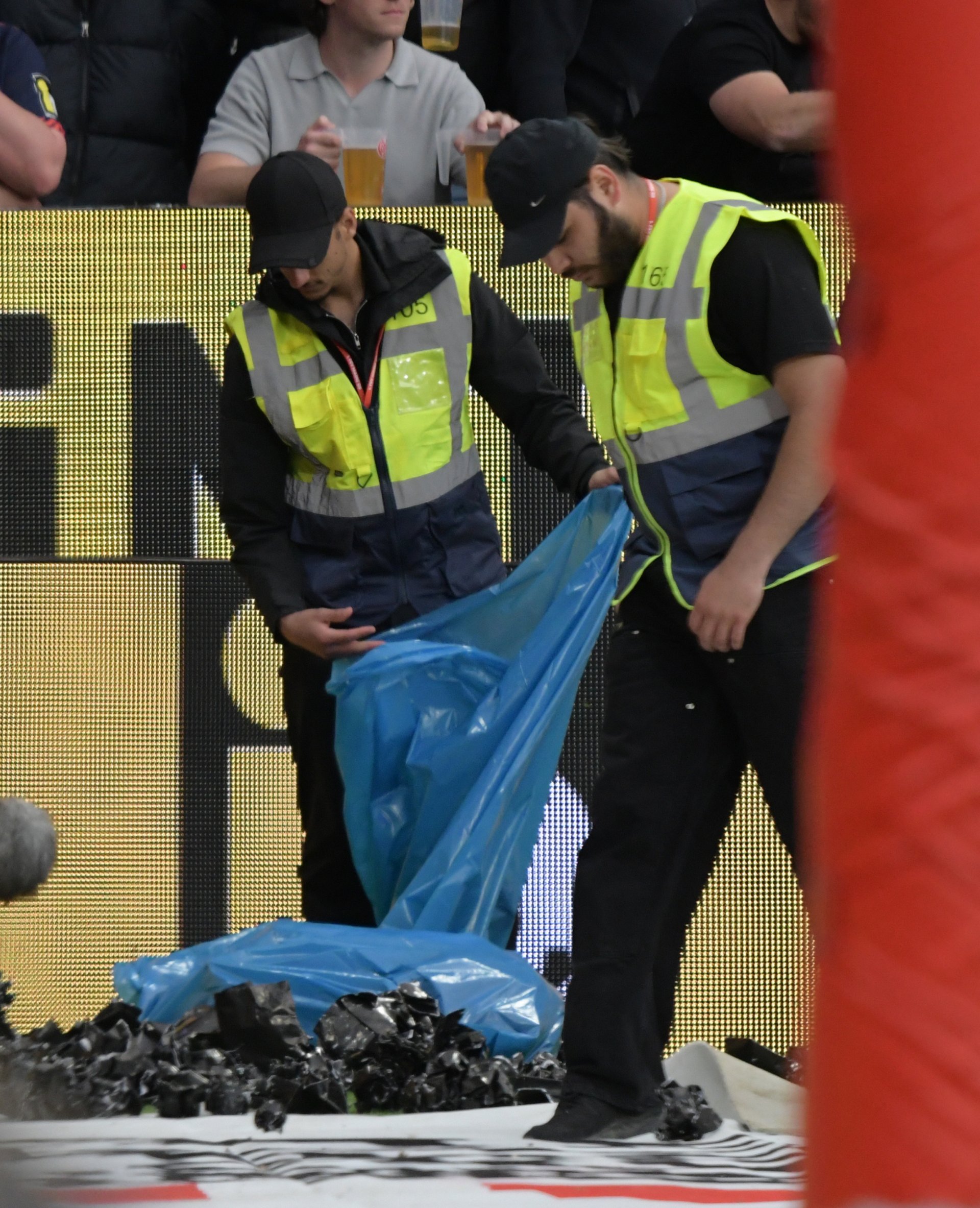 Ordner räumen den Frankfurter Müll weg, der nach einer halben Stunde aus dem Gästeblock aufs Feld geflogen war.