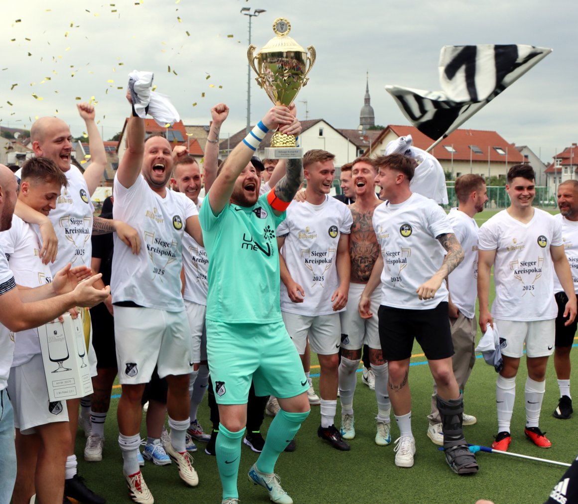 Matthias Everding, Torwart und Kapitän des 1.FC Schwabsburg, stemmt den Pokal in die Höhe.